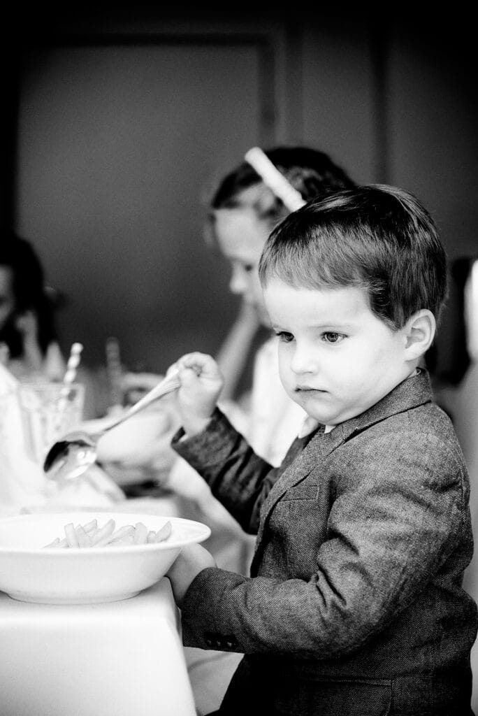 Zamyślony, poważny chłopiec podczas przyjęcia Komunijnego