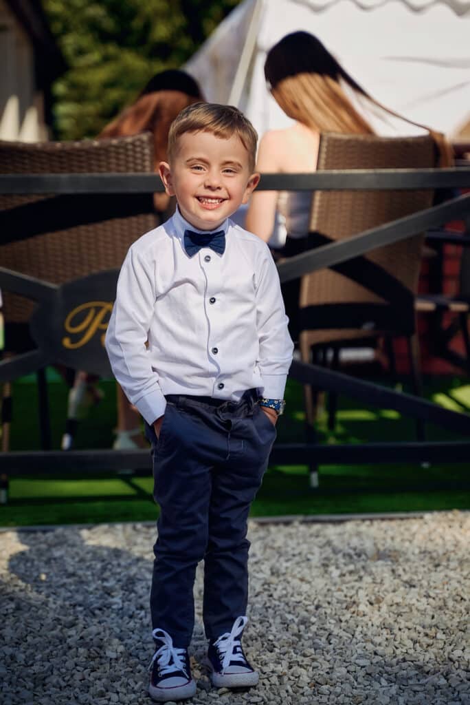 Uroczy chłopiec z rękami w kieszeniach - reportaż komunijny