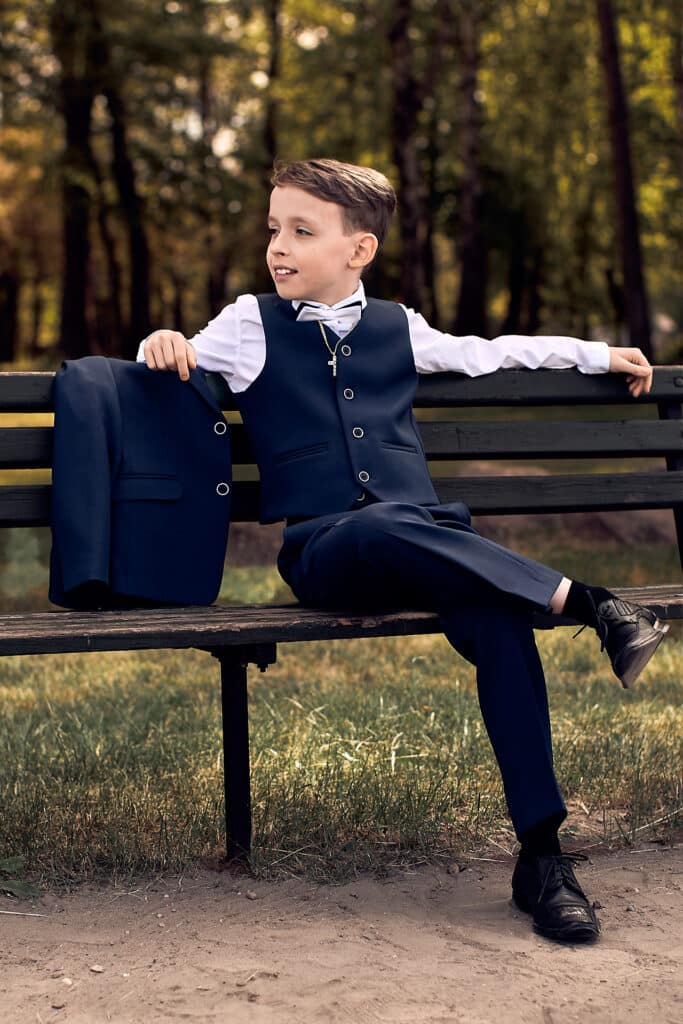 Chłopiec pierwszokomunijny siedzi na ławce - sesja fotograficzna