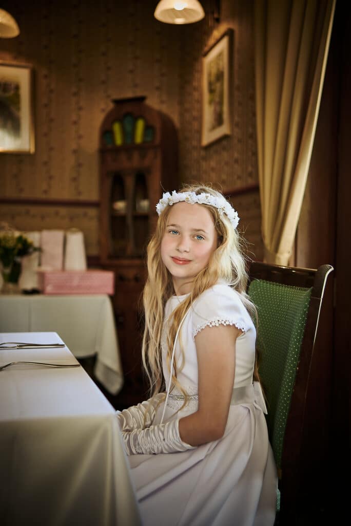 Pierwszokomunijna dziewczynka za stołem