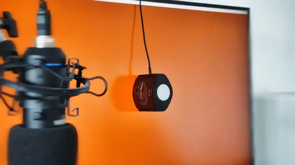 Kolorymetr Calibrite ColorChecker Studio leżący na kilku wydrukowanych wzornikach kolorów i skalach szarości, w tym Epson L-Series. Zestaw ten jest używany do profilowania drukarek i tworzenia dokładnych profili ICC, co jest kluczowe dla precyzyjnej reprodukcji barw i zarządzania kolorem w druku.