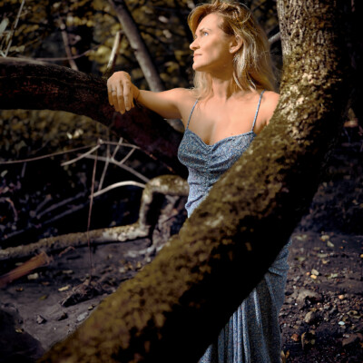 Modelka stojąca przy drzewie patrzy w słońce