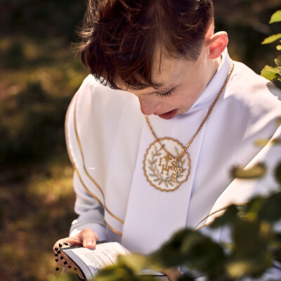 Sesja Komunijna - chłopie modli się z książeczką.