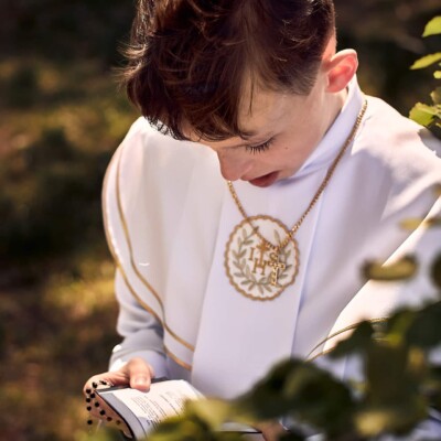 Sesja Komunijna - chłopie modli się z książeczką.