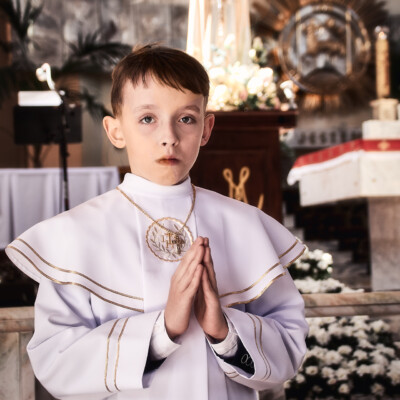 Chłopiec pierwszokomunijny modlący się w kościele Kolbego